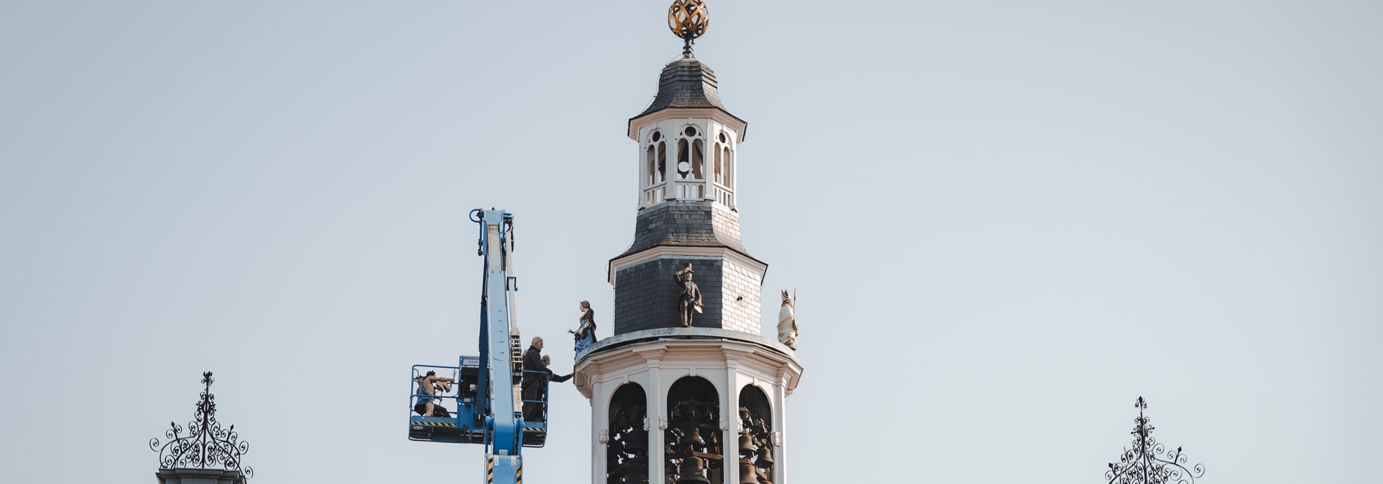 Toren van een kerk met koepel en klok tegen een heldere lucht.