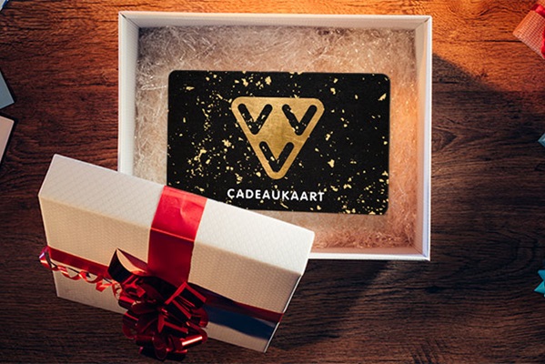 A gift card in an open box with a red ribbon, lying on a wooden table.