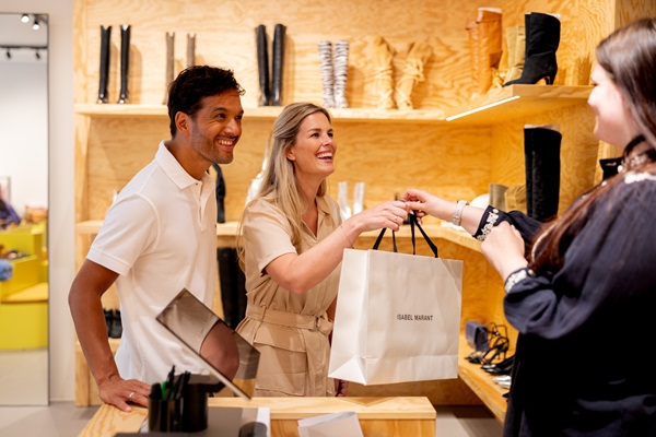 A couple is handed a shopping bag by a saleswoman in a shoe shop at the Designer Outlet Roermond.